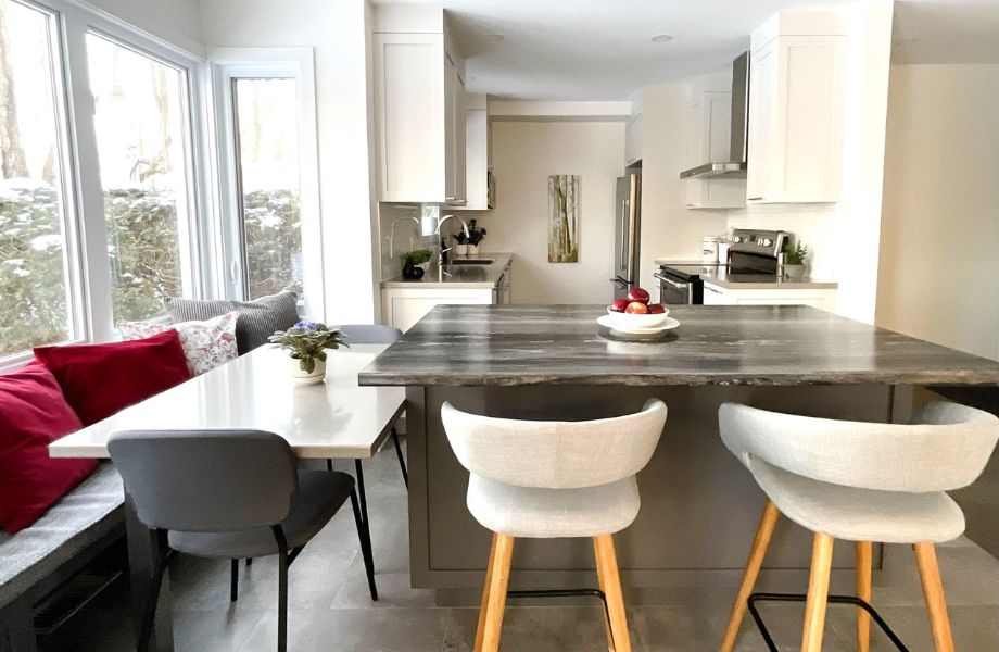 Island with laminate countertop, fruit bowl, white dining table and kitchen with white cabinets