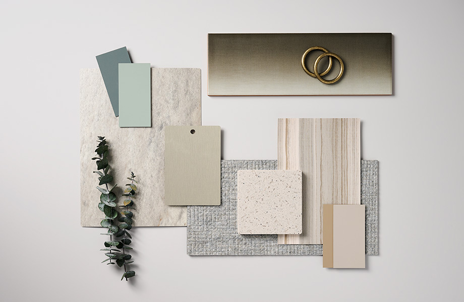 Rectangular samples of green, tan, metallic and cream surfaces along with dried green plant arranged in a designer’s palette