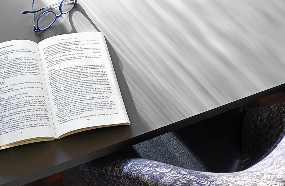 Gray table top with open book, eyeglasses and chair