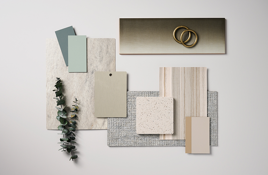 Rectangular samples of green, tan, metallic and cream surfaces along with dried green plant arranged in a designer’s palette