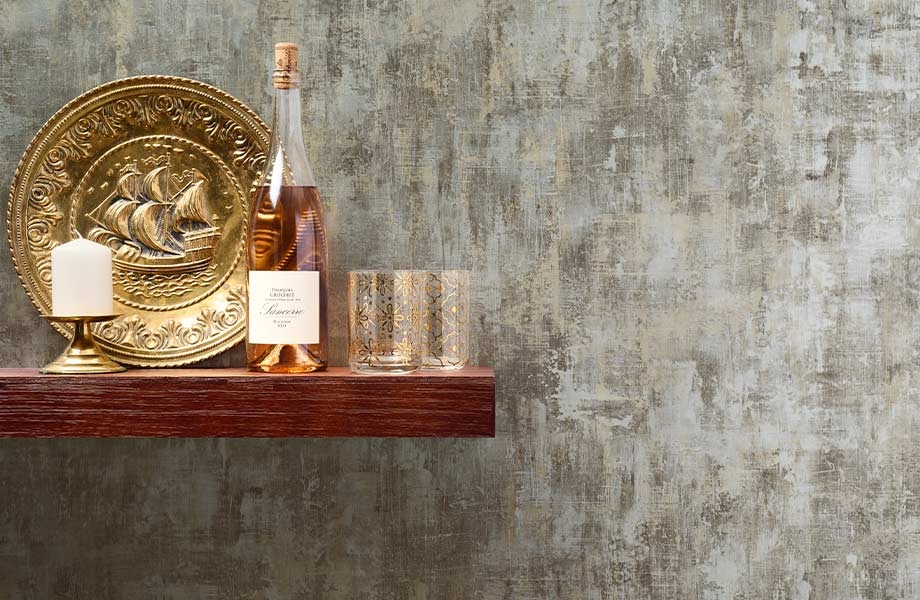 Wooden floating shelf with large gold plate, wine and glasses set against Metallic Gilt Homapal Metal Laminate accent wall