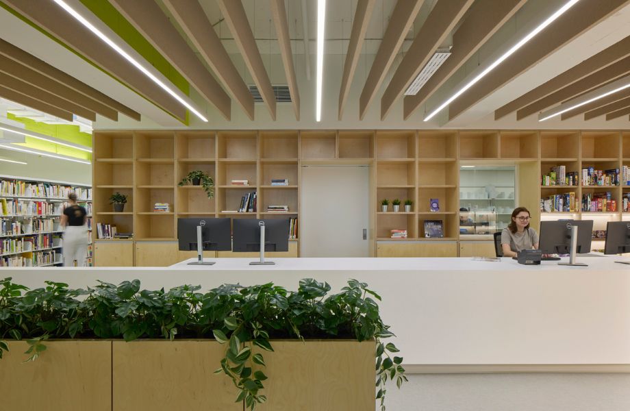 Comptoir de réception blanc avec ordinateurs noirs et étagère murale en bois