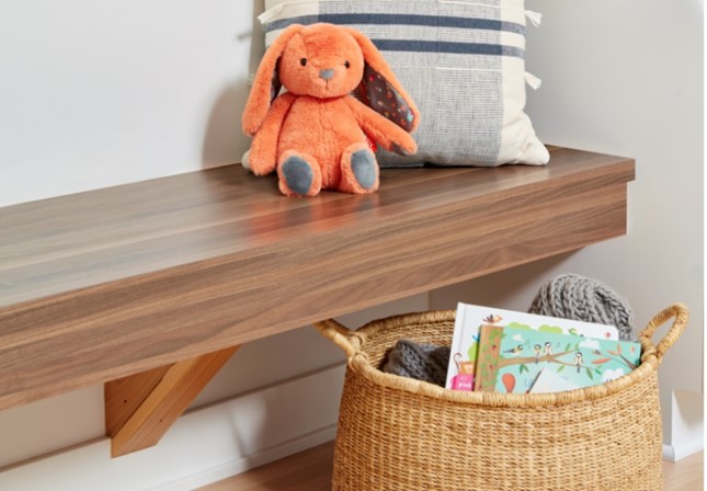 Banc en stratifié de marque Formica Noyer d’Étal avec animal en peluche, coussin et panier de livres