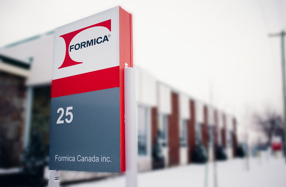 Plan rapproché du panneau d'entrée des bureaux de Formica Canada avec le logo et le bâtiment en arrière-plan