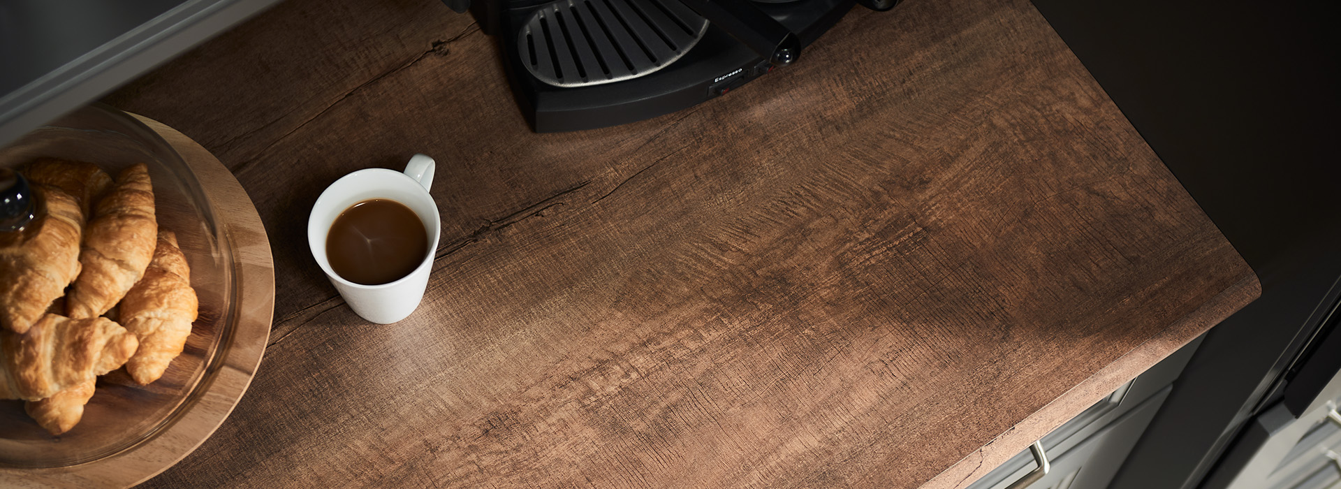 Comptoir de cuisine en bois foncé avec tasse à café et assiette de croissants